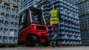 Person i varsel passerar bakom en Linde motviktstruck